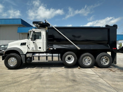 Dump truck side view showing a white cab and black dump body with chrome exhaust, six rear wheels, and a lifting bar. No visible text on vehicle.