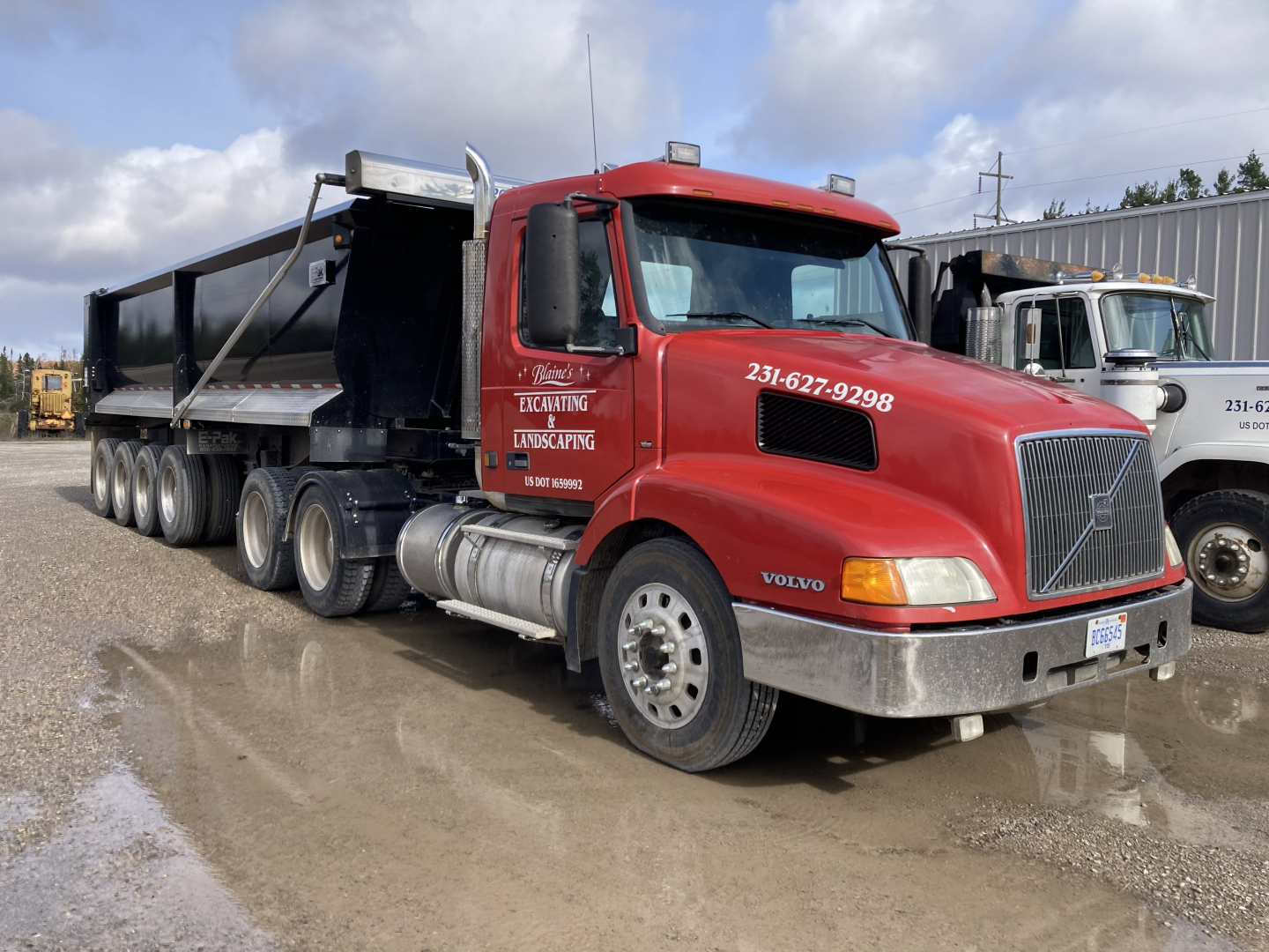 Volvo DD S60 dump truck showing red cab and black dump bed with multiple axles and chrome grille, in a muddy lot.