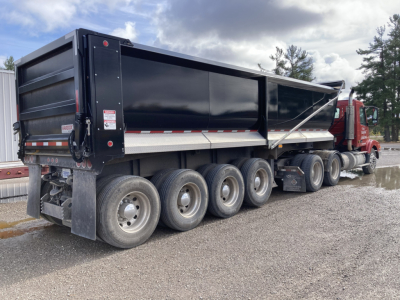 Volvo DD S60 dump truck side view showing black dump bed and multi-axle trailer with red cab.