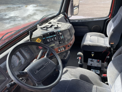 Volvo DD S60 truck interior showing steering wheel, instrument cluster, dashboard controls, and gray fabric seats with center console and gear shifter.