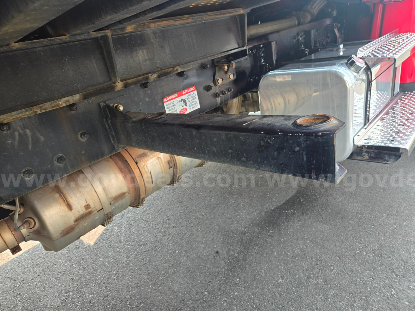 Freightliner M2 chassis showing exhaust, frame rail, and fuel tank from rear side with step platform.