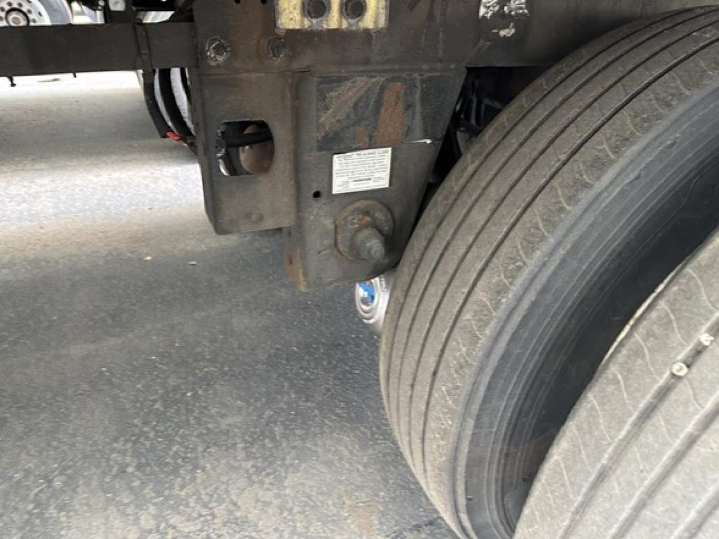Trailer chassis and dual rear tires with metal frame and small white label visible on the underside near a hitch, 2018 Utility 3000R Reefer trailer.