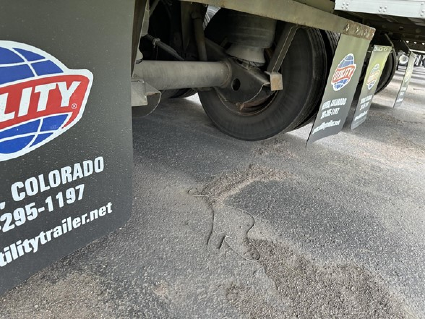 Trailer undercarriage of a 2018 Utility 3000R reefer trailer showing tire, suspension, and mudflap with Utility logo stickers.