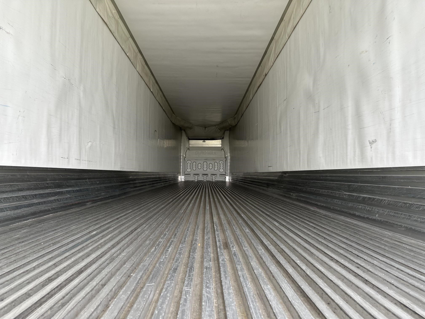 Interior of a Utility 3000R trailer trailer cargo area with ribbed floor and white sidewalls, view toward the front nose. Shows empty refrigerated trailer interior.