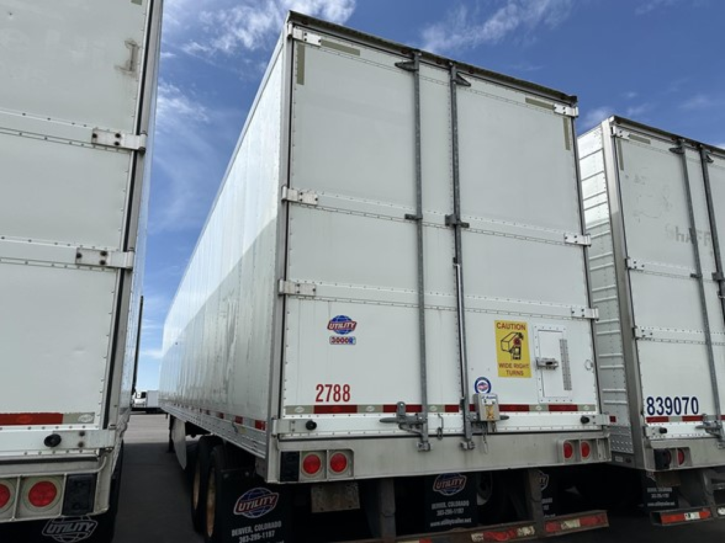 Trailer rear view showing Utility 3000R refrigerated trailer with closed doors and CAUTION sticker.