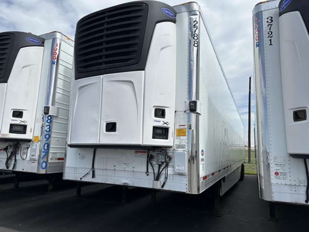 Utility 3000R trailer refrigeration unit with black front cooling grille and white body, side doors, and multiple trailers in a row.