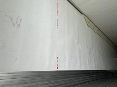  Trailer interior wall in a reefer trailer showing blank white surface with faint red tape marks.