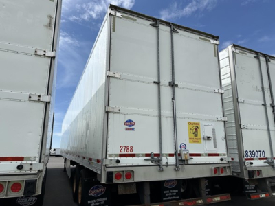 Trailer rear view showing Utility 3000R refrigerated trailer with closed doors and CAUTION sticker.