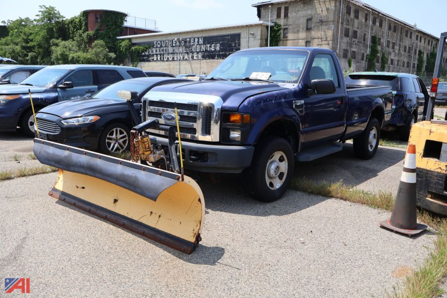 Ford F-250 pickup truck with a snow plow attachment in the foreground, blue cab, 4x4, used condition, other vehicles in background
