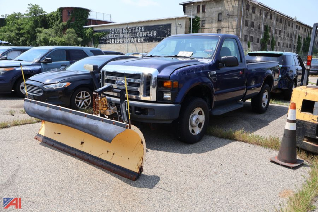 Ford F-250 pickup truck with a snow plow attachment in the foreground, blue cab, 4x4, used condition, other vehicles in background