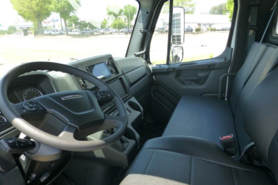 Freightliner M2 106 cab interior showing steering wheel, dashboard, and front bench seat in a clean, utilitarian cab.