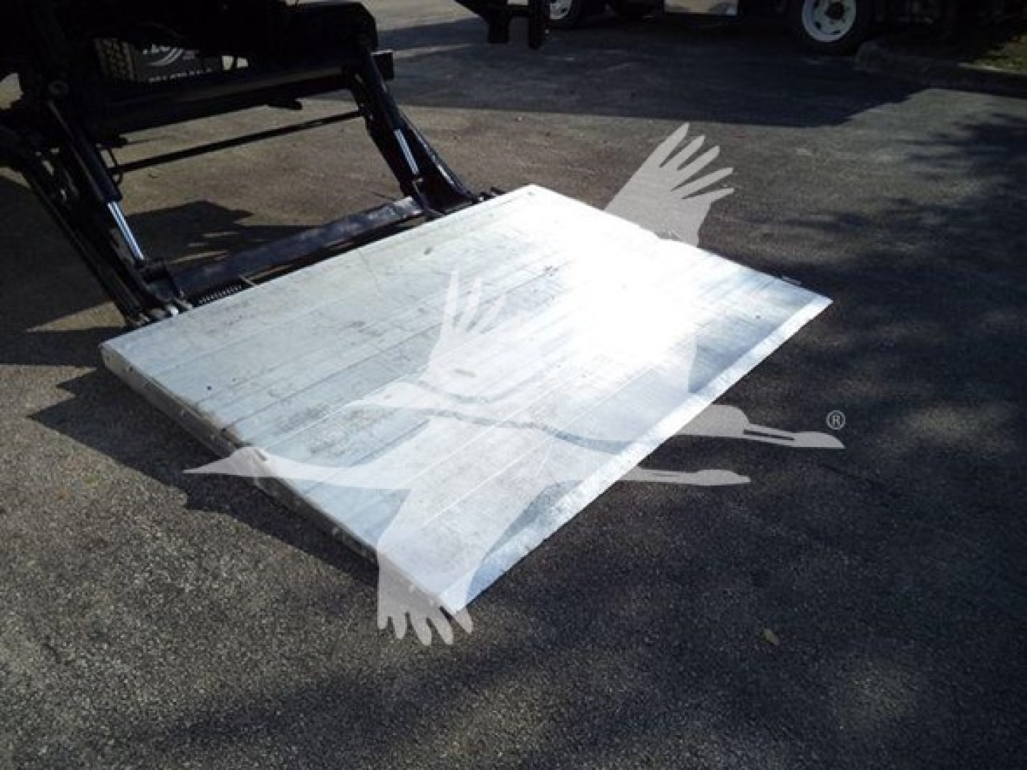 Platform ramp and forklift attachment on a refrigerated truck body with blank metal surface.