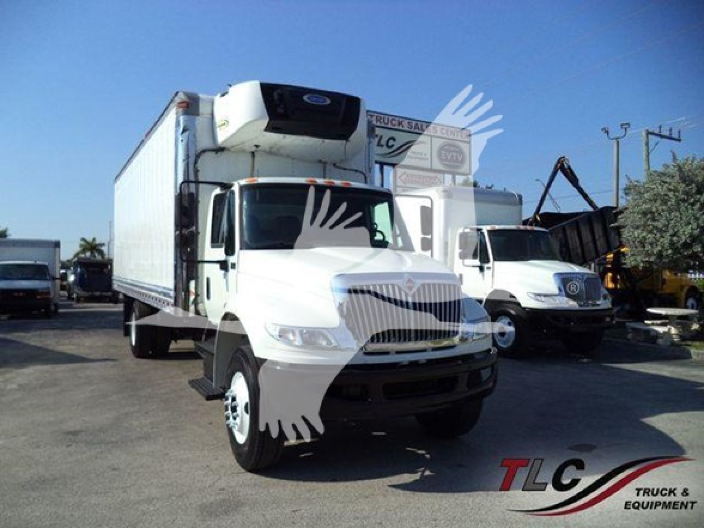 International DuraStar 4300 refrigerated truck with a box trailer, front grille, cab with attached refrigeration unit on top, other truck in background.