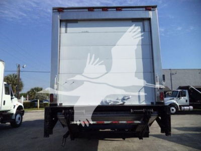 Back of a refrigerated box truck with a lift gate and white graphic on the door. No legible model text visible.