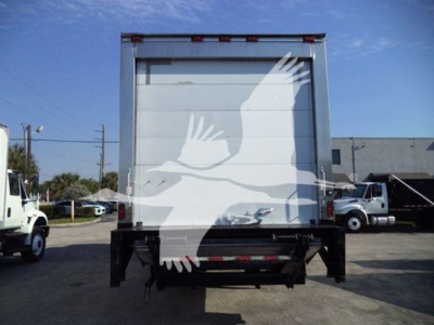 Rear view of a refrigerated box truck with a large roll-up door. Visible text includes VIN label area and stock number plate.