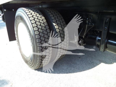 Truck rear wheel and suspension undercarriage with dual tires and underbody components visible.