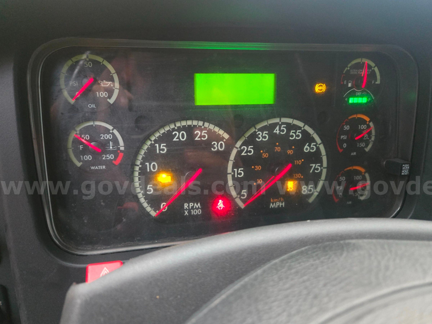 Dashboard of a 2019 Freightliner M2 shown with multiple gauges, warning lights, and a bright green center display.