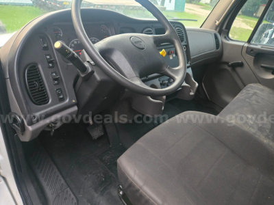 Cab interior of a 2019 Freightliner M2 truck showing steering wheel, dashboard, and driver's seat with controls