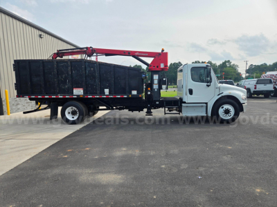 Truck side view showing a white Freightliner M2 with a black dump body and red hydraulic crane arm for grappling loads.