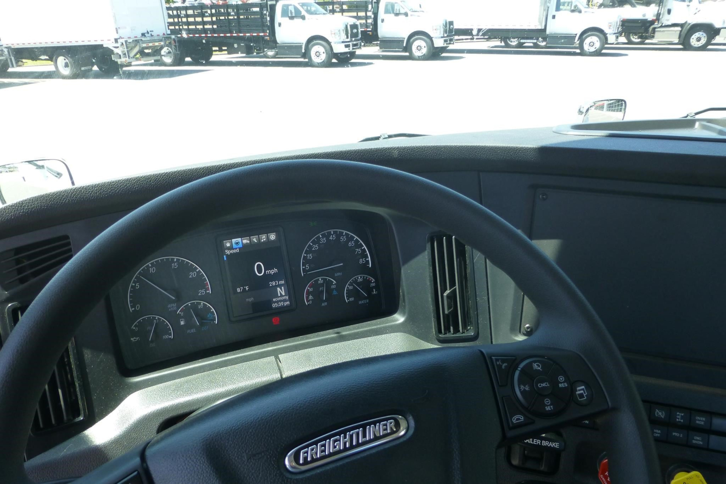 Freightliner Cascadia truck cabin dashboard view showing steering wheel with Freightliner emblem and instrument cluster.