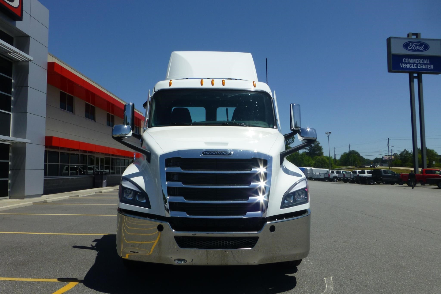 Front view of a white Freightliner Cascadia day cab truck with chrome grille and bumper.