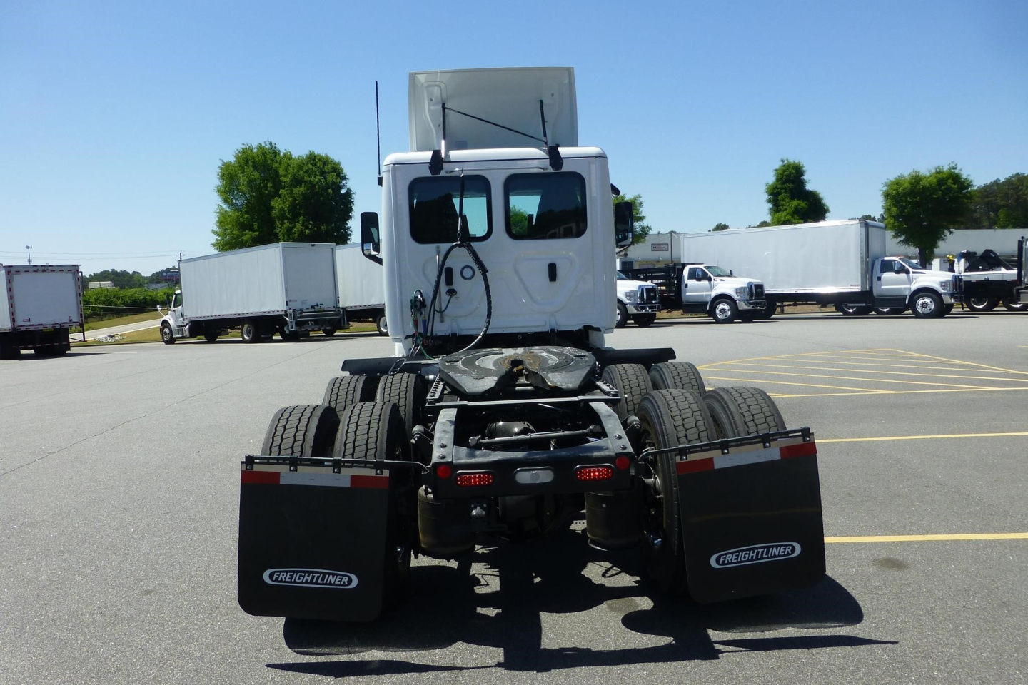 Freightliner Cascadia day cab rear view showing chassis, dual rear axles, mud flaps, and fifth wheel mount.