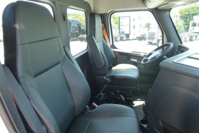Truck cab interior showing driver seat and passenger seat in a Freightliner Cascadia cab with steering wheel and dashboard visible.