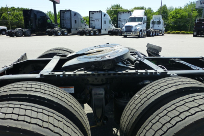 Truck chassis view showing fifth wheel plate and dual rear axles with tires and frame members of a freightliner Cascadia tractor.