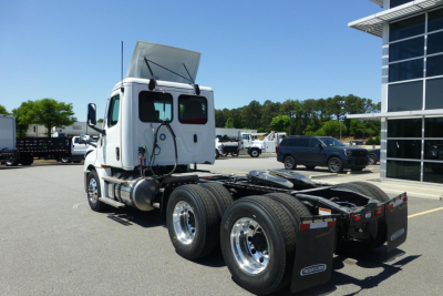 White Freightliner Cascadia day cab tractor viewed from rear-left showing chassis, dual rear axles, fuel tanks, and exhaust stack. No visible warning text.