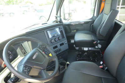 Freightliner Cascadia truck interior showing steering wheel, dashboard with touchscreen display, center console, and driver seat from inside the cab.