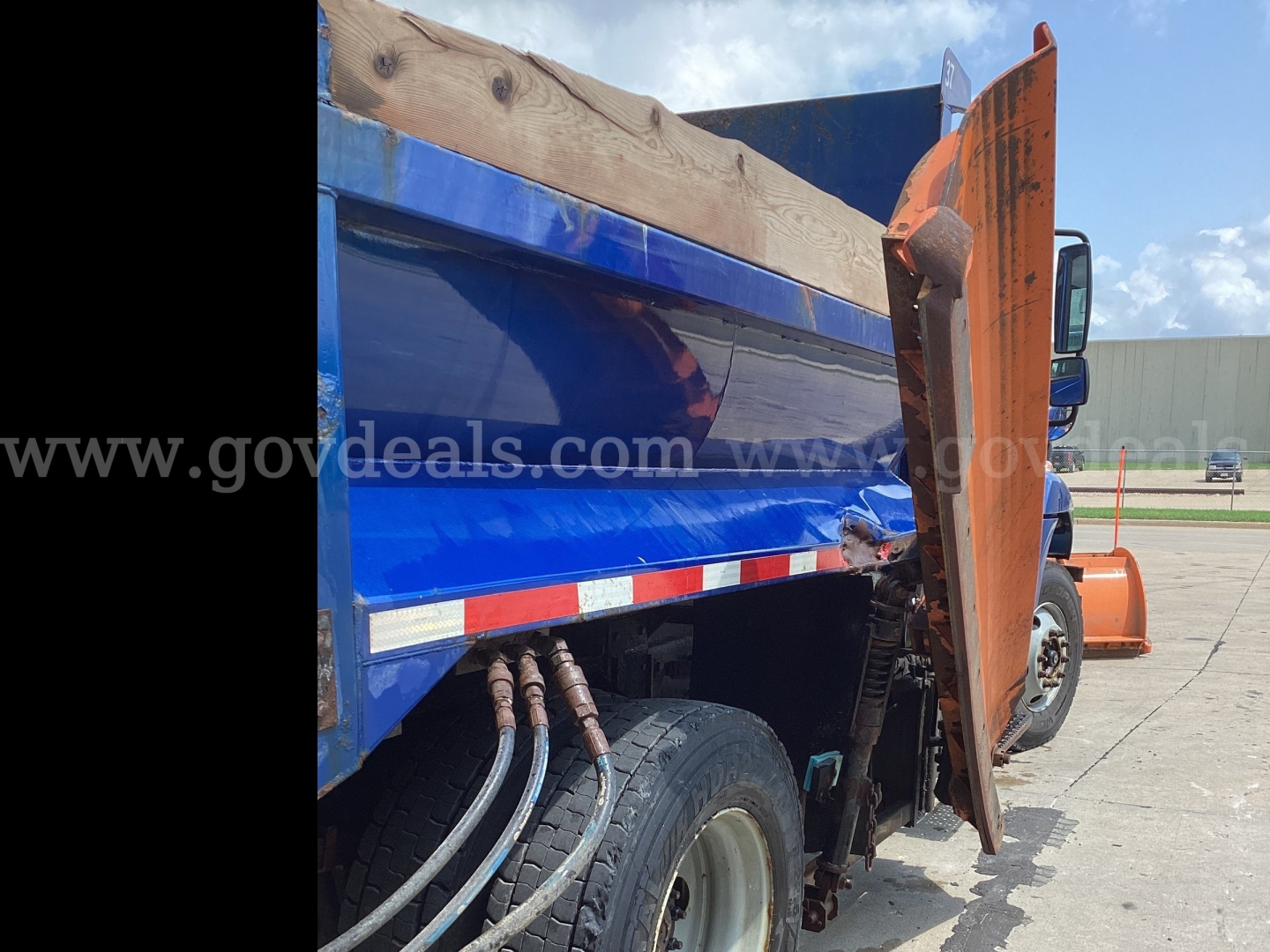 Truck side view showing hydraulic hoses and blue dump bed of a 2016 International 7300 plow truck.