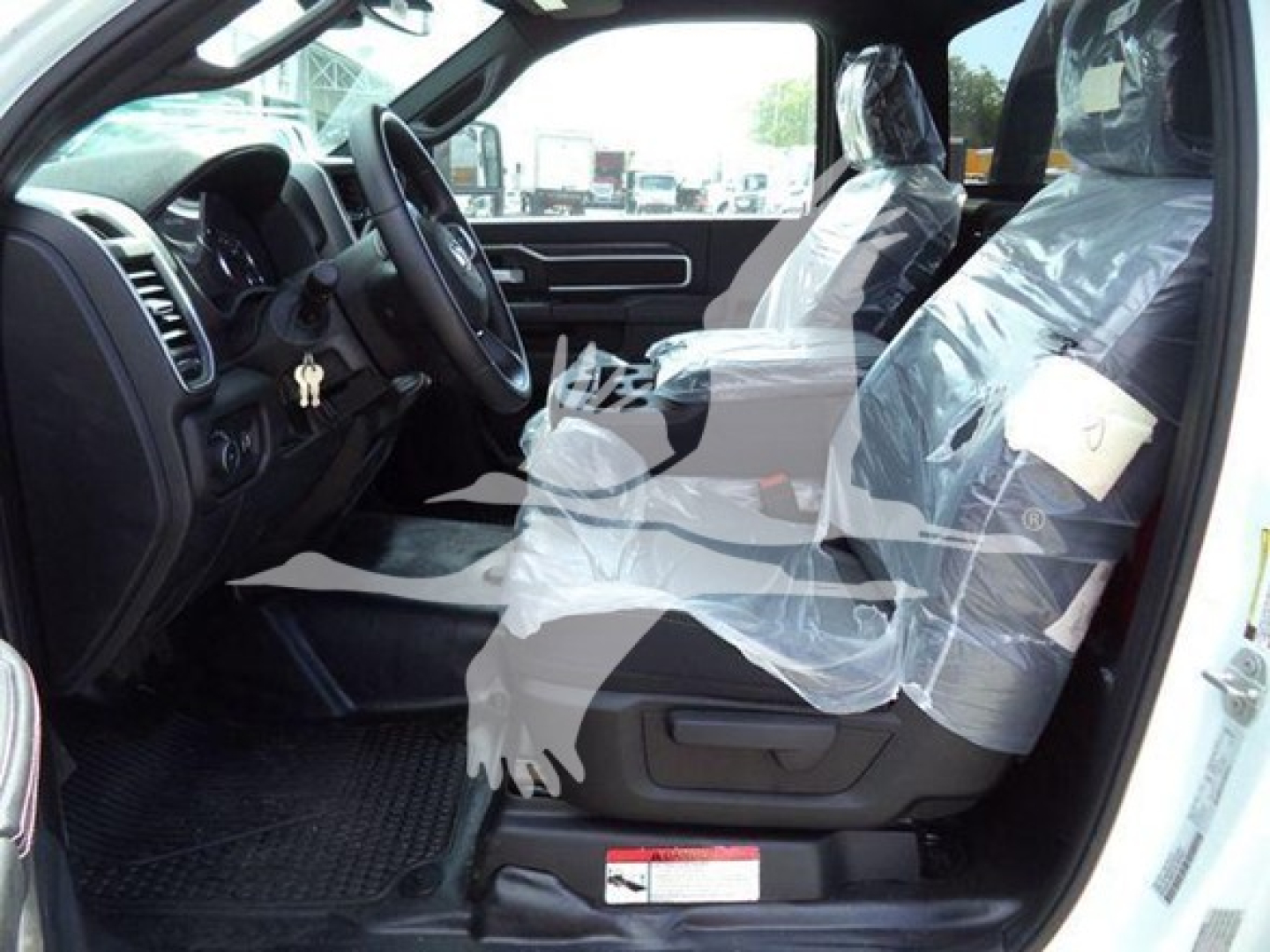 Truck interior with front seats wrapped in plastic showing steering wheel and dashboard of a Ram 5500 SLT.