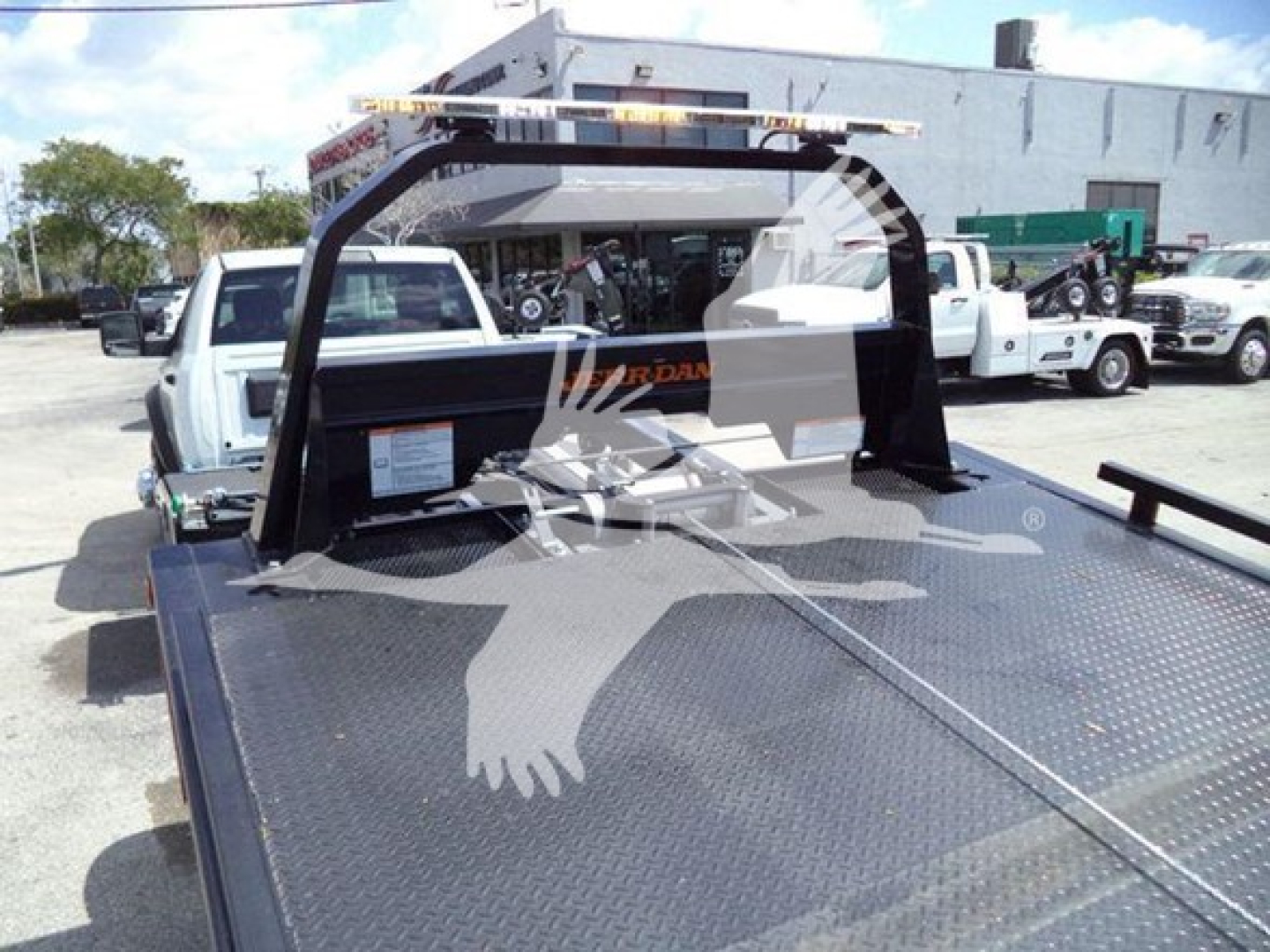 Ram 5500 rollback truck bed with metal diamond plate, rear cab guard, and surrounding dealership lot visible.