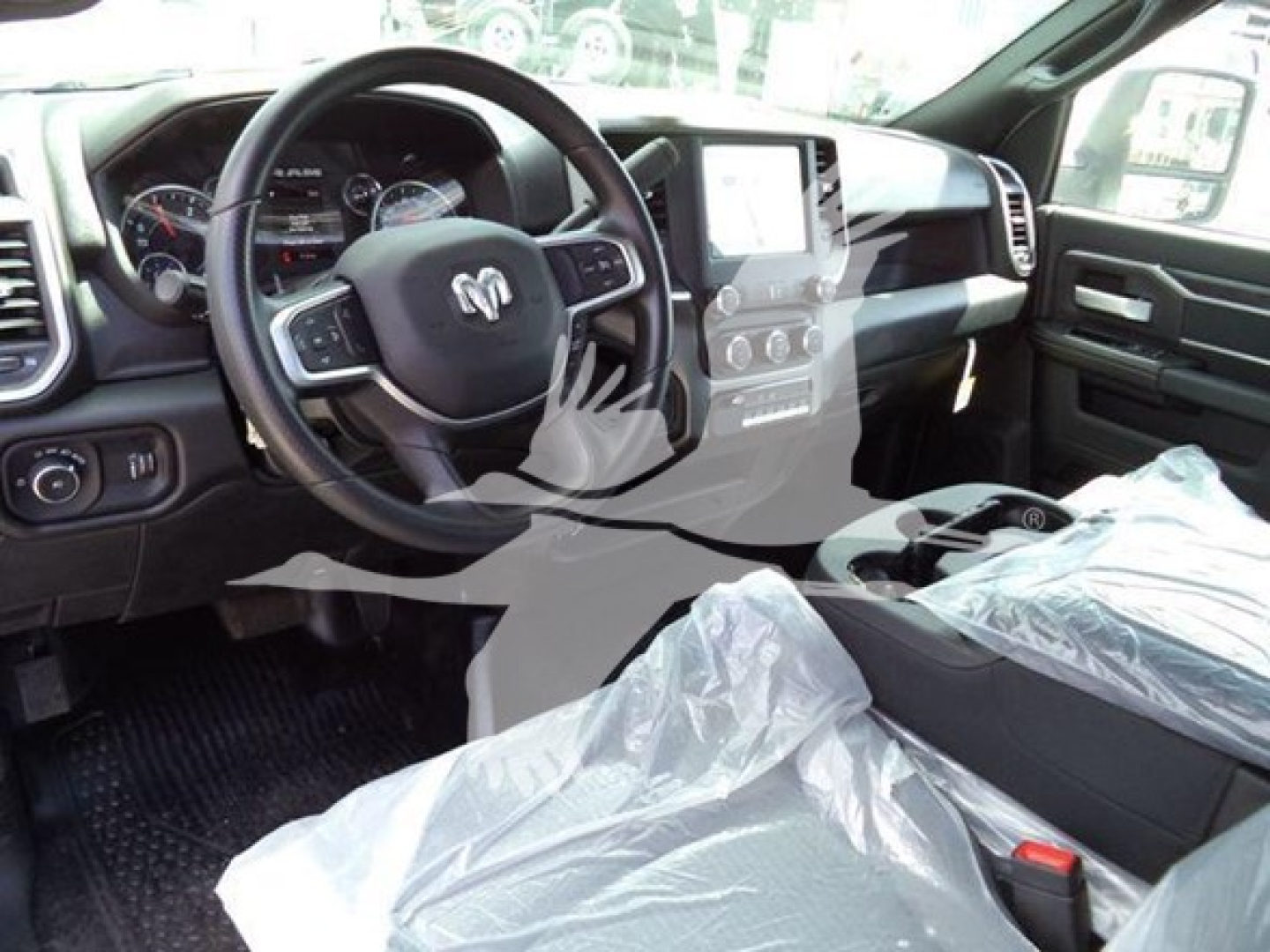 Ram 5500 interior dashboard view with steering wheel and center console; plastic seat covers on front seats; dashboard screen and controls visible