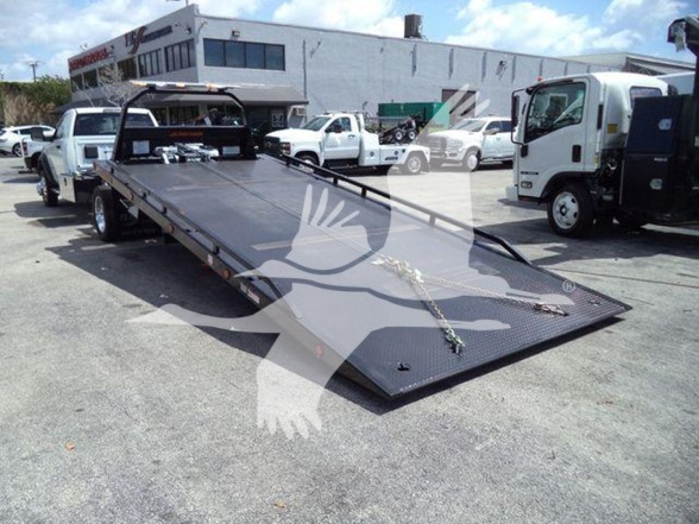 Ram 5500 rollback flatbed tow truck showing long tilted steel platform and rear ramps.