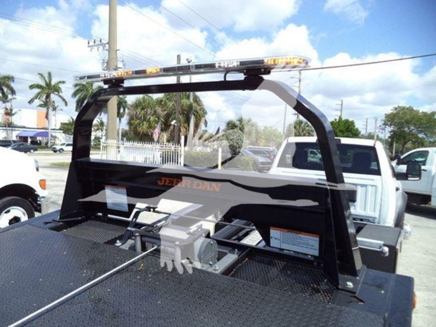 Ram 5500 rollback truck bed with hydraulic winch and optional light bar, rear view showing steel hauler bed and tailgate posts.