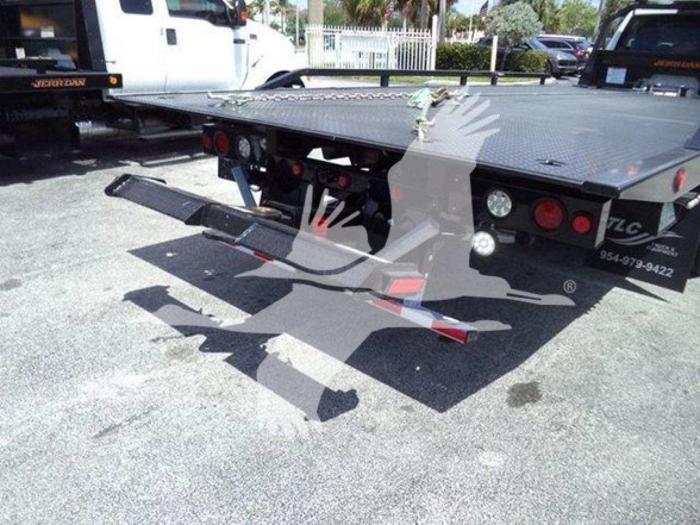 Ram 5500 rollback truck rear view showing flatbed and ramp accessory with lights and towing hitch.