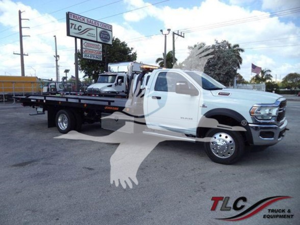 Ram 5500 tow truck in white and black, rollback bed, side view showing extended ramp bed and dual rear wheels.