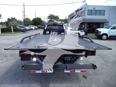 Ram 5500 rollback tow truck flatbed rear view showing rear lights and safety chains attached to the bed.