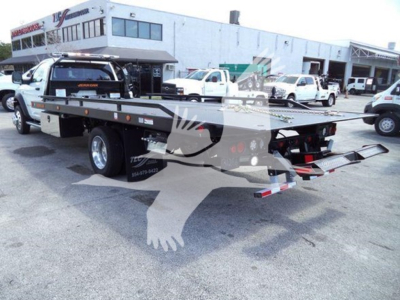 Ram 5500 rollback tow truck flatbed with dual rear ramps and hydraulic lift, white color, dealership lot in background, visible stock number J40687.