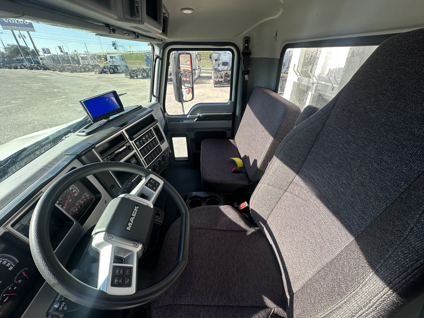 Mack MD6 truck cab interior showing steering wheel, dashboard, and front seats with large side window and side mirror.