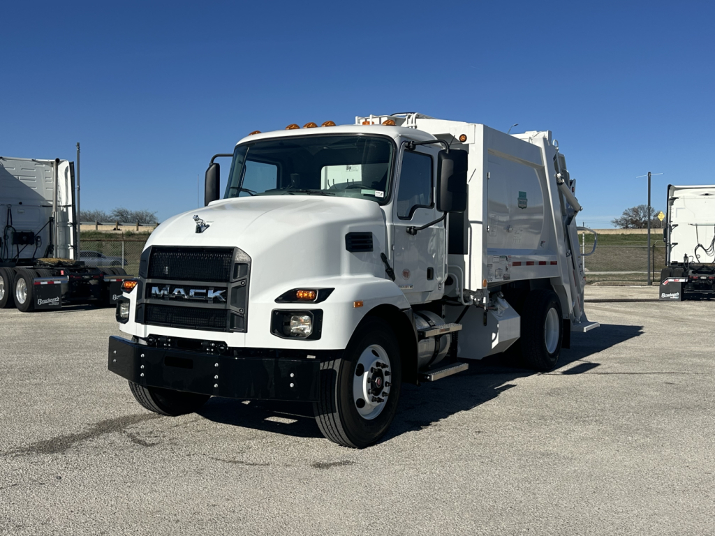 White Mack MD6 refuse truck angled front-left showing cab with chrome grille, black bumper, amber cab marker lights, and a large white rear compactor body.