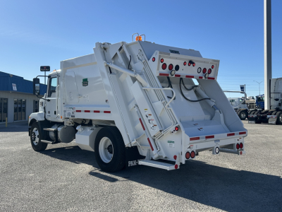 Mack MD6 refuse truck body side and rear view showing lift system and rear hopper with hydraulic components and warning lights.