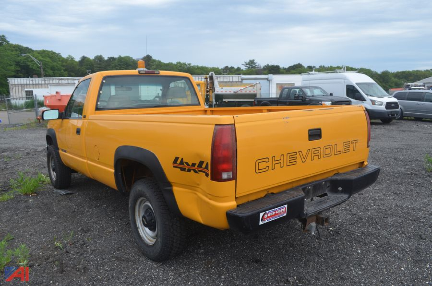 Chevrolet C/K 2500 single cab pickup truck in yellow parked in lot showing rear and passenger side