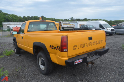 Chevrolet C/K 2500 single cab pickup truck in yellow parked in lot showing rear and passenger side
