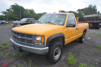 Chevrolet C/K 2500 series pickup truck 1997 in yellow/orange with single cab, front grille and bumper, 4x4 badge not visible, in a salvage lot.