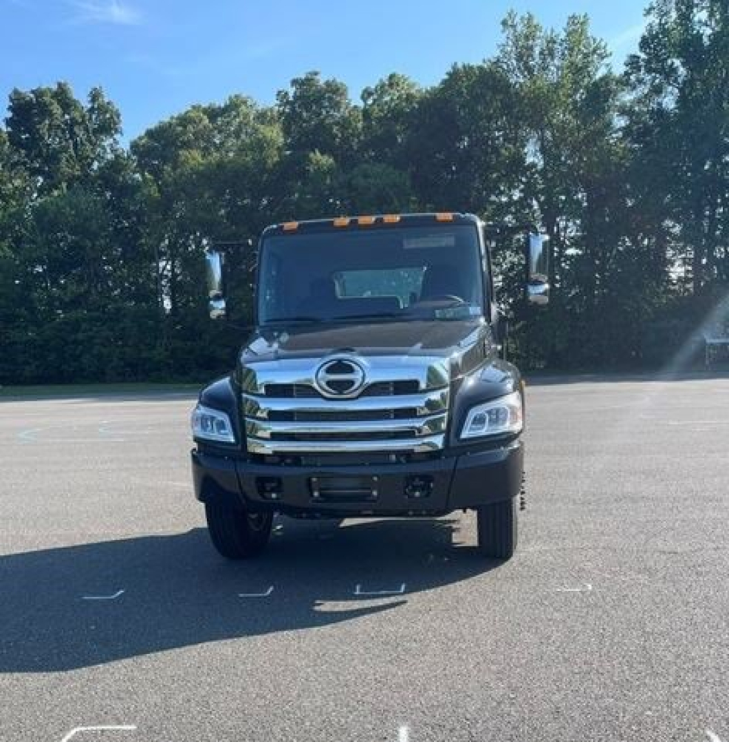 Front view of a new 2027 Hino L7 cab chassis truck in a parking lot showing chrome grille, Hino emblem, and large headlights.