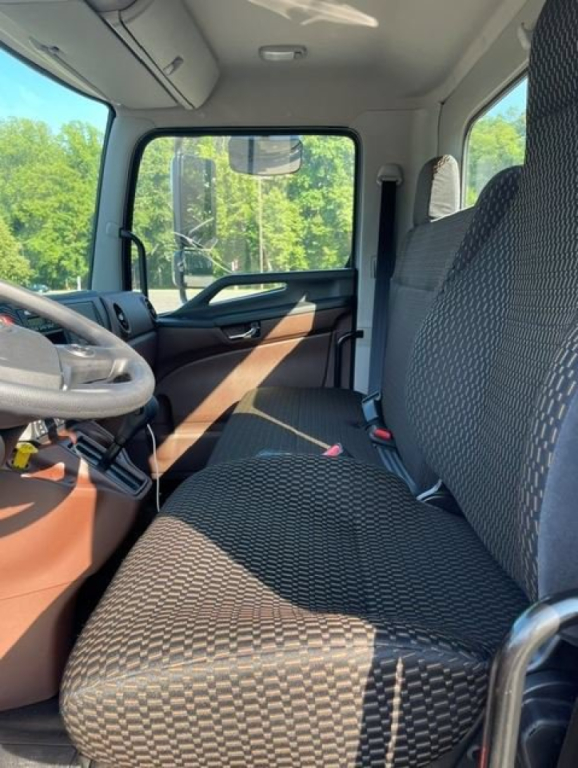 Cab interior of a 2027 Hino L7 truck showing front bench seat, steering wheel, and dashboard with patterned upholstery.