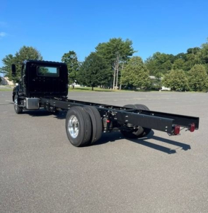 Hino L7 cab chassis truck in a parking lot, long wheelbase flat frame with dual rear wheels and minimal bodywork visible.
