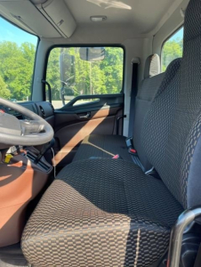 Cab interior of a 2027 Hino L7 truck showing front bench seat, steering wheel, and dashboard with patterned upholstery.